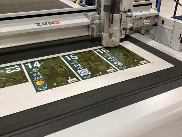 Disc golf tee signs being laser-cut with rounded corners on a CNC machine