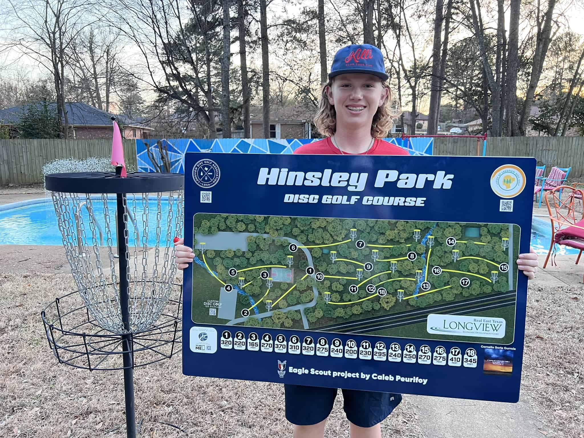 Installed custom disc golf tee sign on a course with sponsor branding