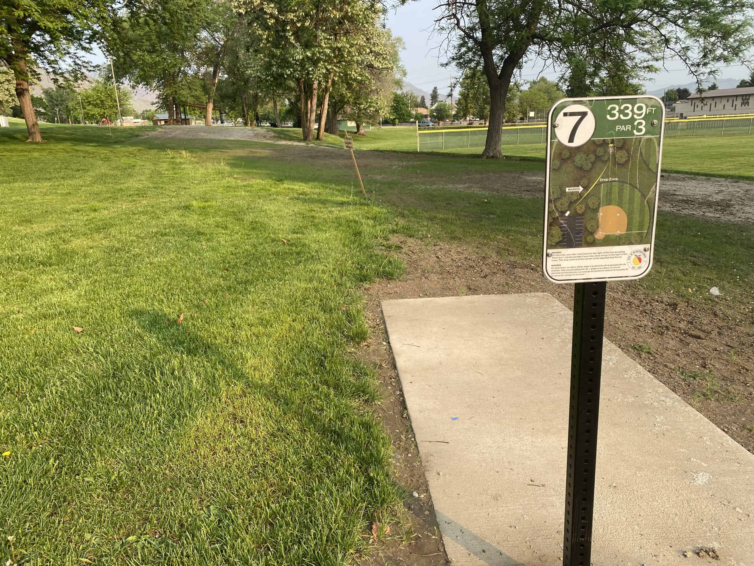 Disc golf course sign showing hole 7 layout and distance at an outdoor park.